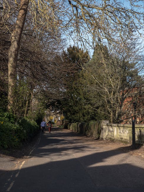A curved red brick wall with a textured surface surrounds a garden area, featuring a narrow white door with an arched top set into the wall. To the left, a small white street sign reading 'CANONBURY' 